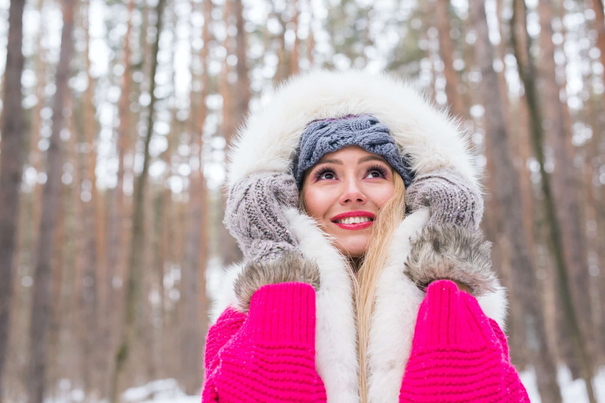 Fashion, winter and people concept - Young attractive woman dressed in fur waistcoat over snowy